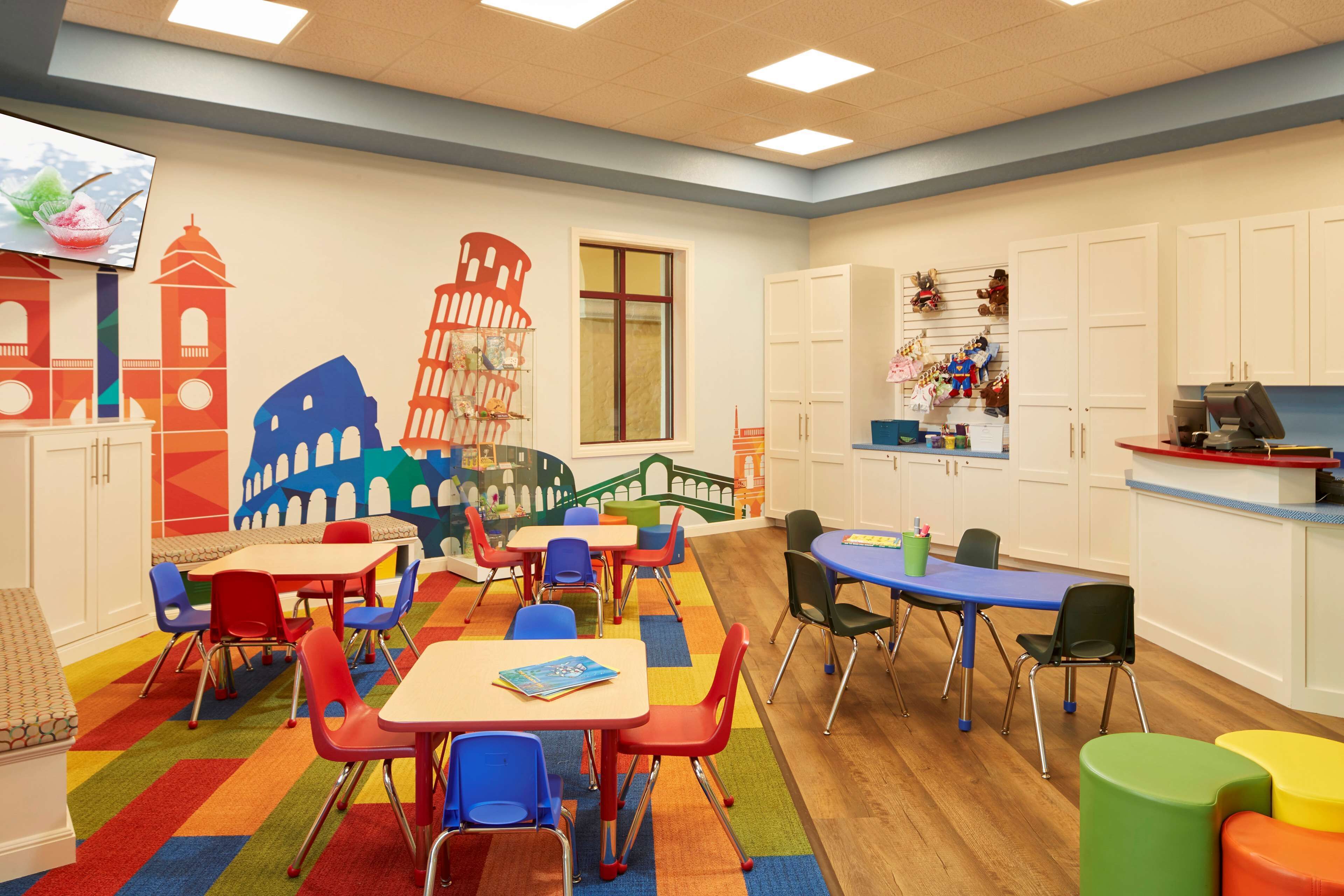 A children's playroom with colorful furniture and educational murals.