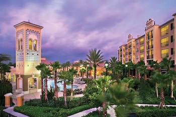 An aerial view of a resort with a central swimming pool, multiple buildings, and a waterfront. at Hilton Grand Vacations Club Tuscany Village Orlando