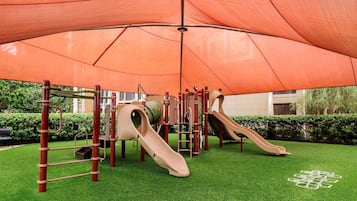 A playground with slides and climbing structures under a large canopy.