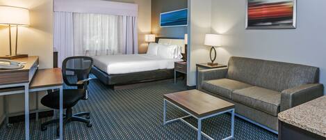 Una habitación de hotel con cama, escritorio, silla, sofá y una mesita.
