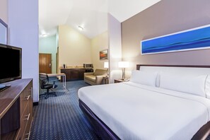 A hotel room with a bed, a desk, a chair, a television, and a painting on the wall.