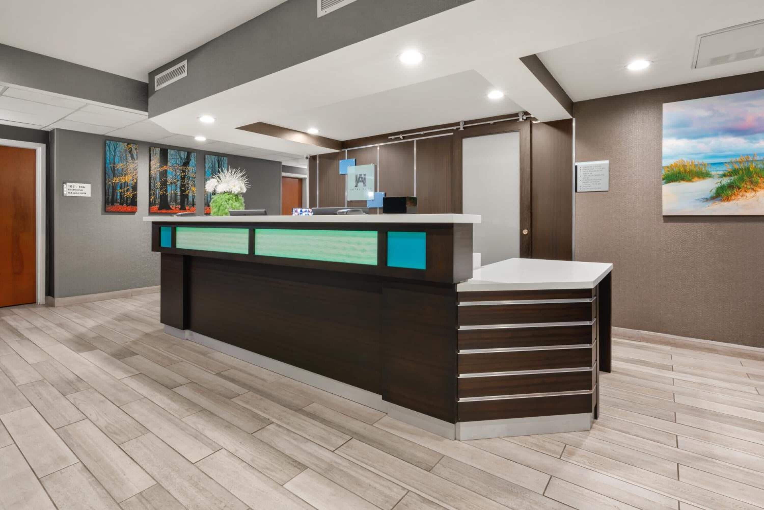 A reception area with a wooden reception desk, a digital display, and artwork on the walls.