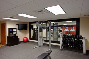 A gym with exercise equipment, a television, and a wall with motivational text.