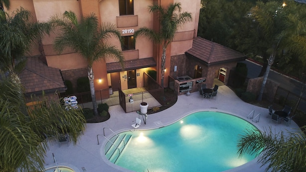 Un hôtel doté d’une piscine, d’un espace extérieur aménagé et de palmiers.