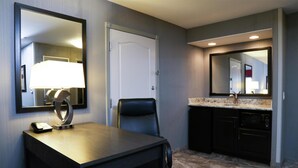 Une chambre d’hôtel équipée d’un bureau, d’une chaise et d’un grand miroir.