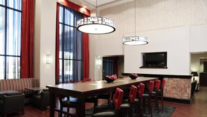 Une chambre d’hôtel dotée d’une grande table à manger, de plusieurs chaises, d’un canapé, d’un téléviseur fixé au mur et d’une cheminée.