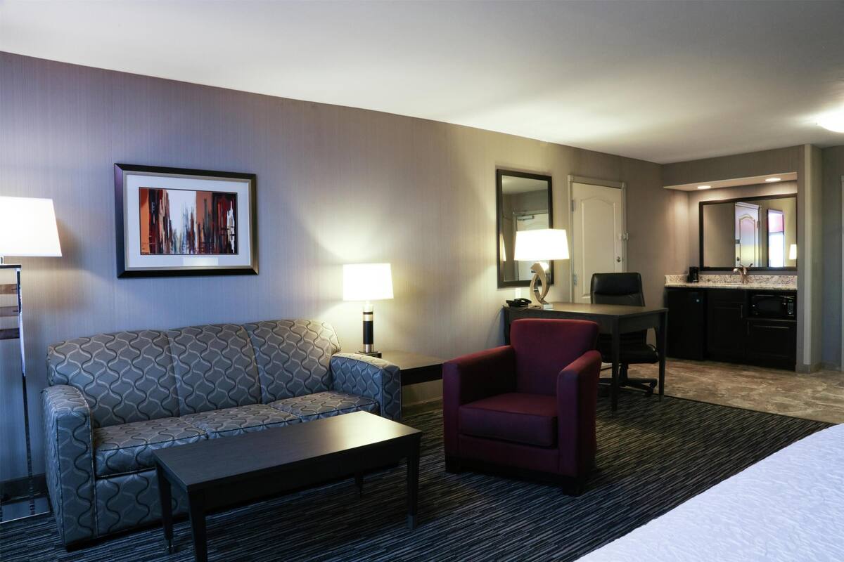 Ein Hotelzimmer mit Sofa, Sessel, Esstisch und Küchenzeile.
