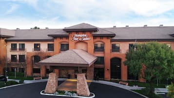 A Hampton Inn & Suites hotel with a covered entrance, multiple balconies, and a landscaped driveway.