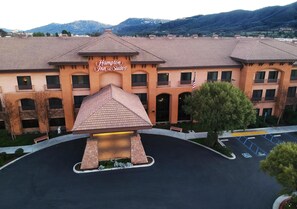 A hotel with a prominent entrance, a covered area, and a parking lot with marked spaces.