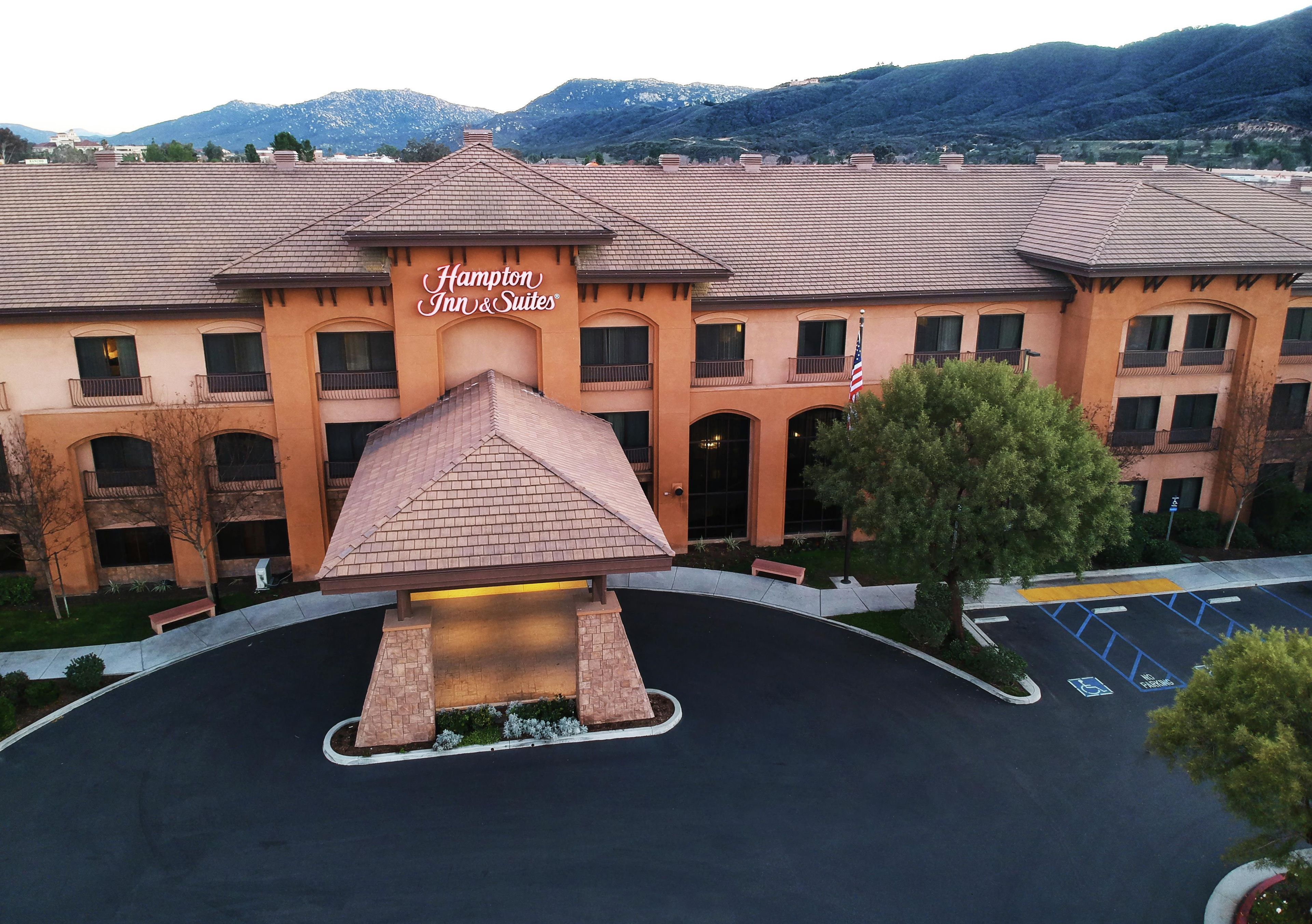 A hotel with a prominent entrance, a covered area, and a parking lot with marked spaces.