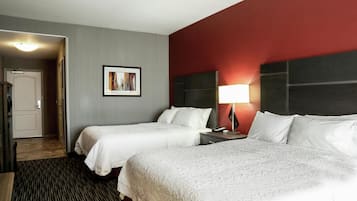 A hotel room with two beds, a nightstand with a lamp, a framed picture on the wall, and a door leading to a hallway.