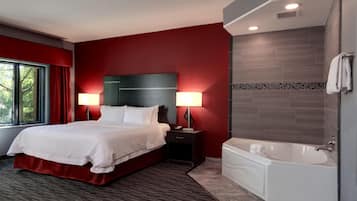 A hotel room with a large bed, bedside lamps, a bathtub, and a window with curtains.
