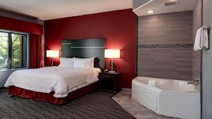 Une chambre d’hôtel avec un grand lit, des lampes de chevet, une baignoire et une fenêtre avec des rideaux.