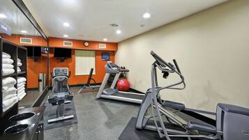 A gym with treadmills, an elliptical, and a red exercise ball.