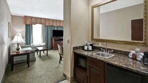 A hotel room with a kitchenette, a large mirror, a sofa, a TV, and a dining area. - Hampton Inn Corpus Christi-Northwest I-37 (Corpus Christi)