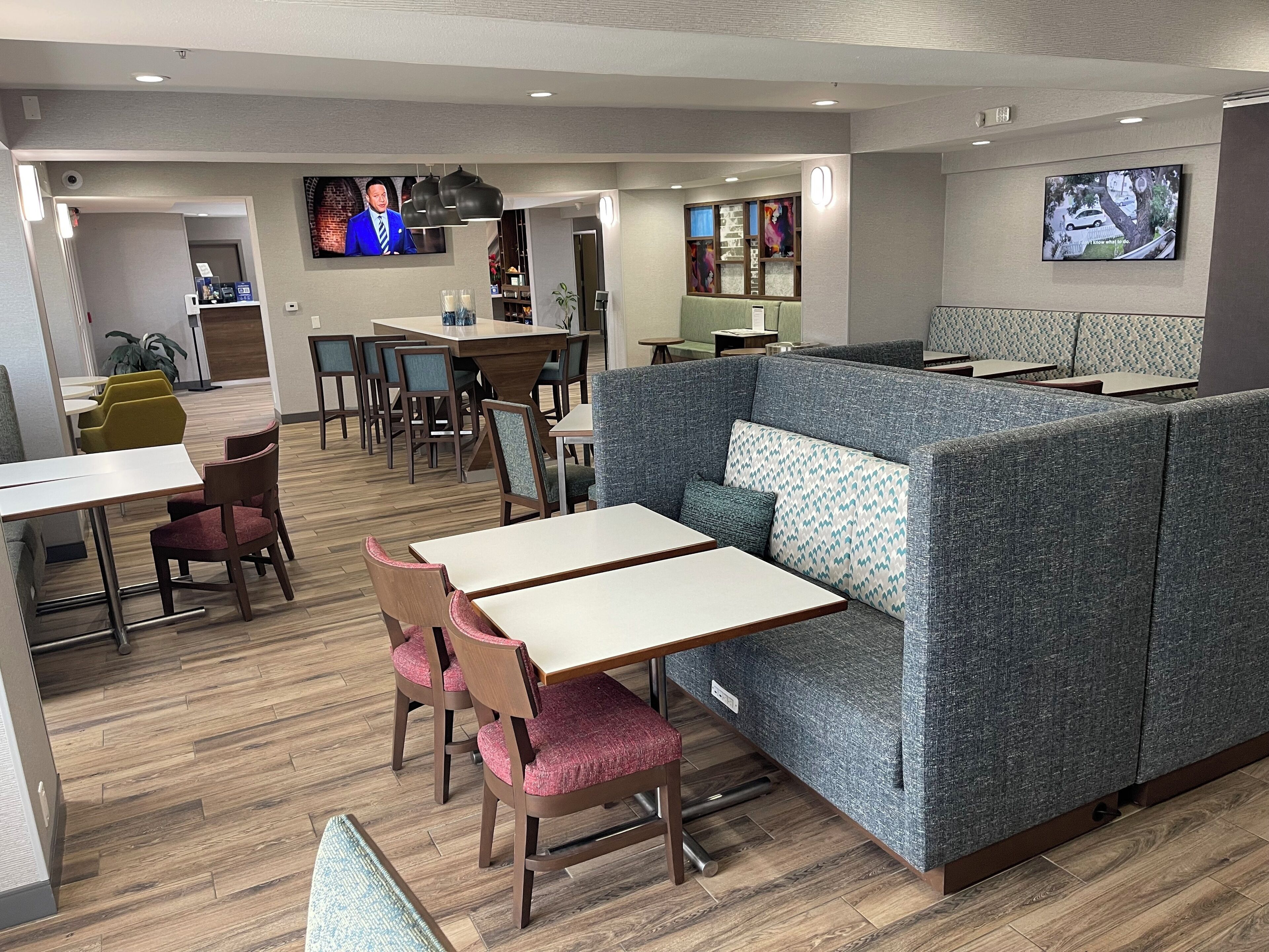 A modern restaurant with booths, tables, and a TV screen.