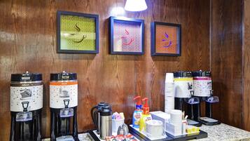 A coffee station with multiple coffee makers and a tray of disposable cups, sugar, and other condiments.