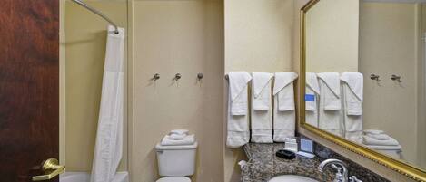 A bathroom with a bathtub, toilet, sink, and a large mirror.