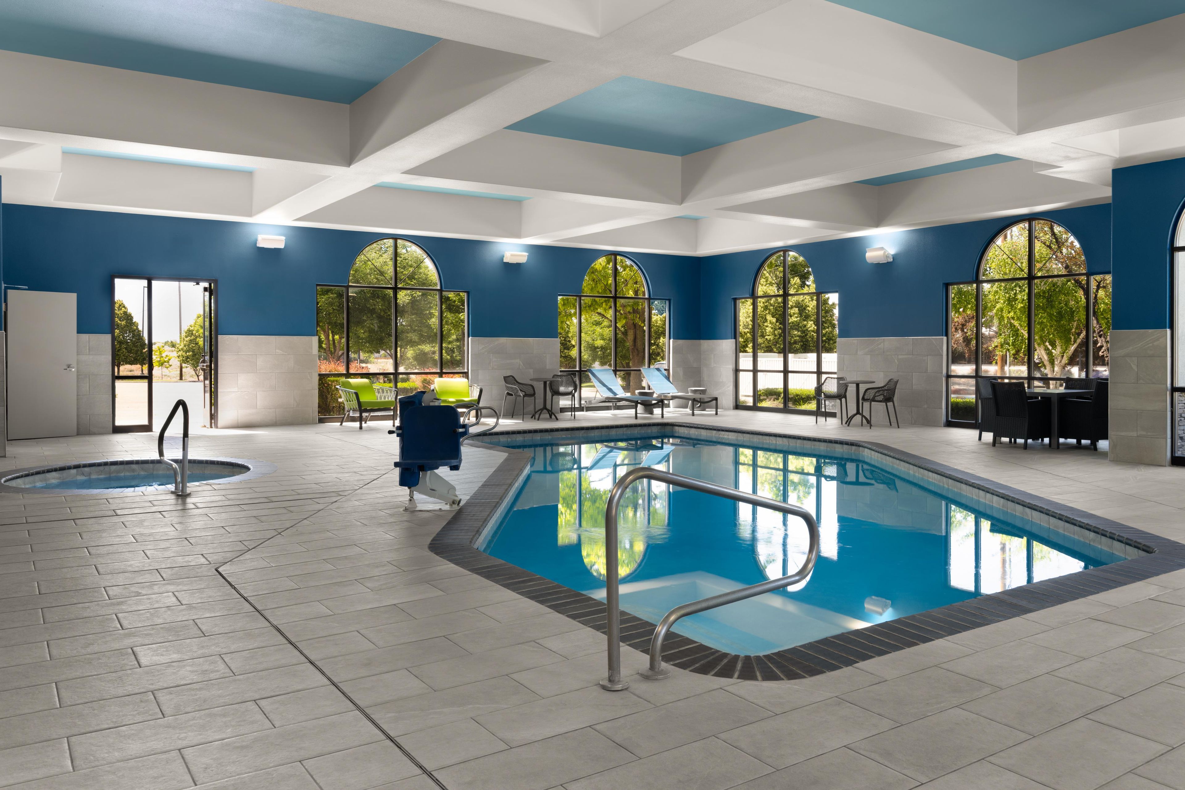 Zona de piscina con trampolín, sillas de descanso y vistas al exterior a través de amplios ventanales.