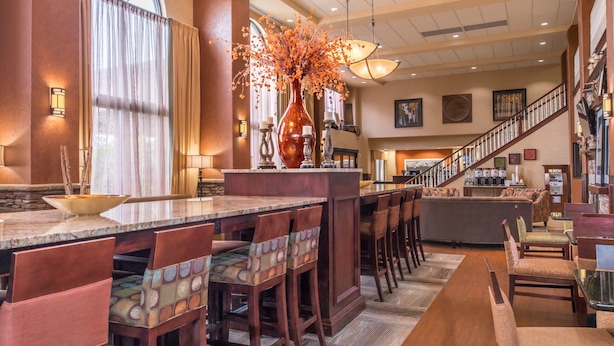 A spacious hotel lobby with a long bar area, comfortable seating, and a staircase leading to the upper floors. - Hampton Inn & Suites Boise-Meridian (Meridian)