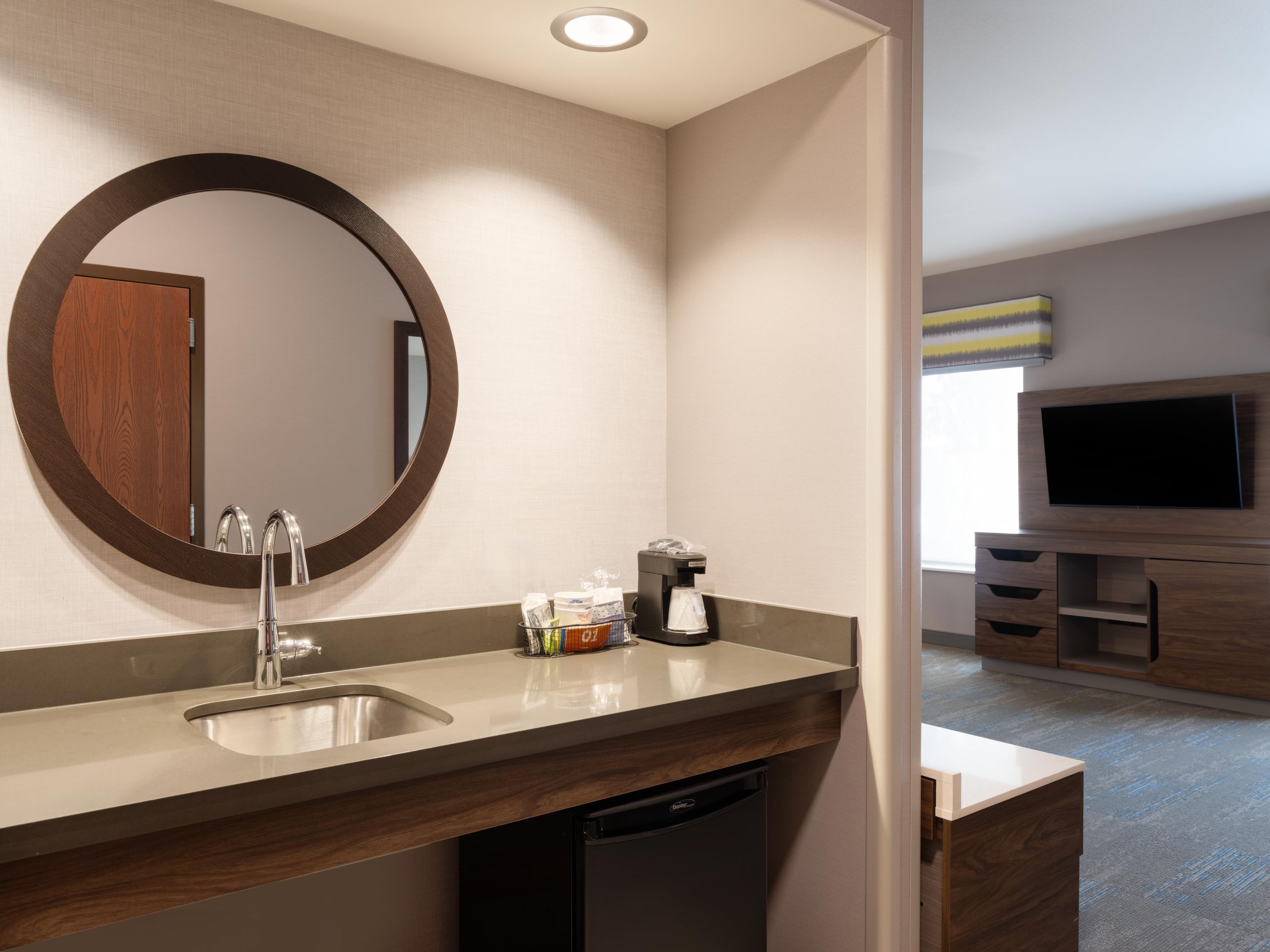 A modern bathroom with a sink, mirror, and coffee machine.