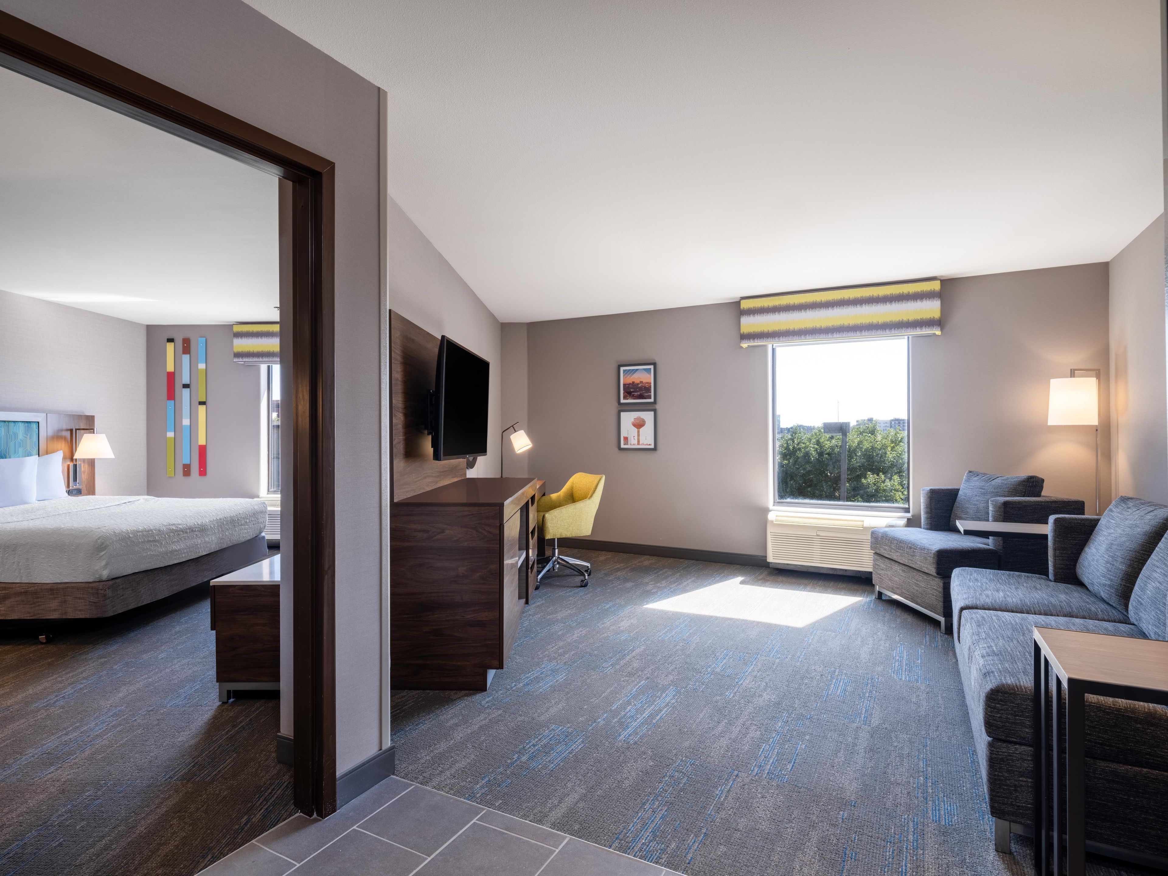 Ein modernes Hotelzimmer mit einem Bett, einem Schreibtisch, einer Couch und einem Fernseher.