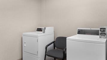 A laundry area with two white washing machines, one with a control panel and the other with a price tag.