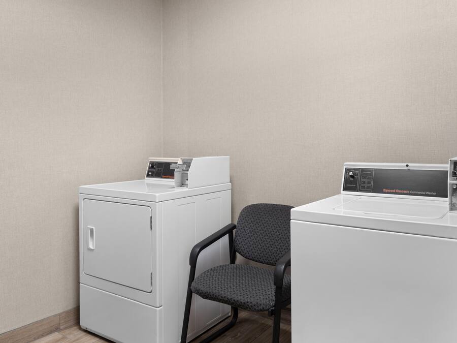 A laundry area with two white washing machines, one with a control panel and the other with a price tag.