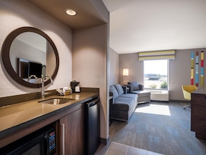 A modern hotel room with a bathroom, a living area with a sofa and armchairs, and a large window offering a view. - Hampton Inn & Suites Boise-Meridian (Meridian)