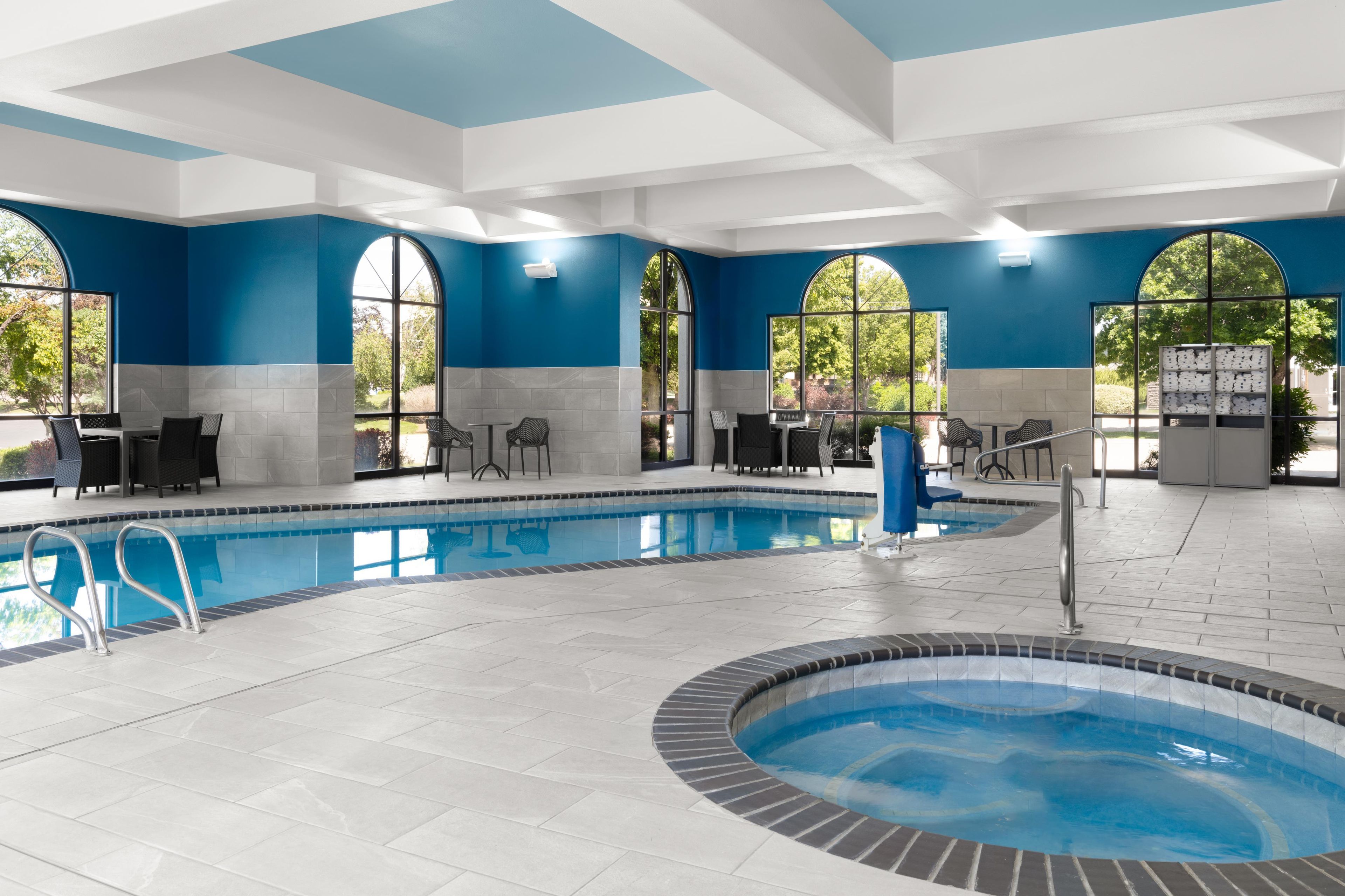 Un área de piscina con jacuzzi, asientos y ventanas amplias.