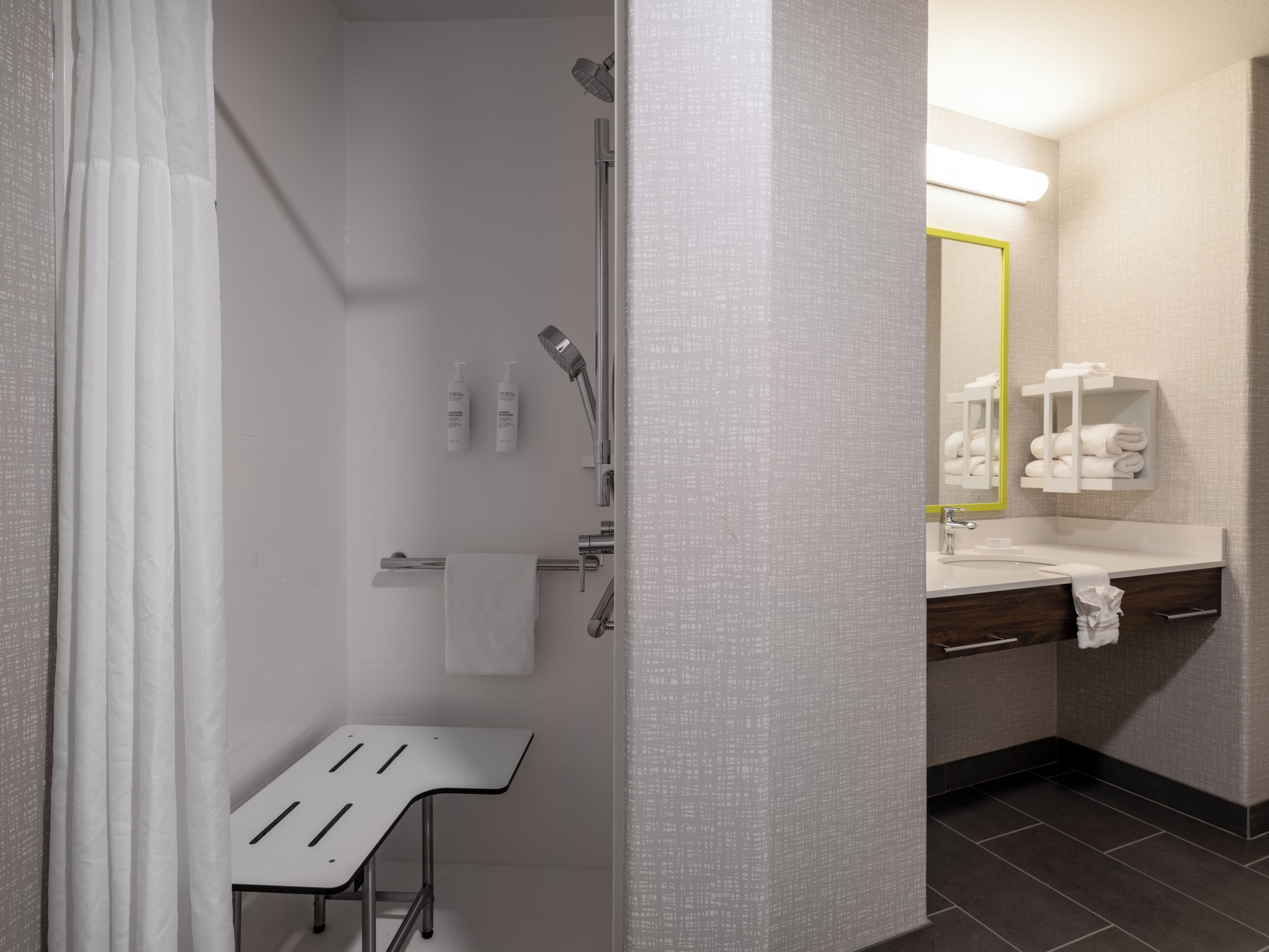 Une salle de bain moderne avec une douche, un lavabo et un miroir.