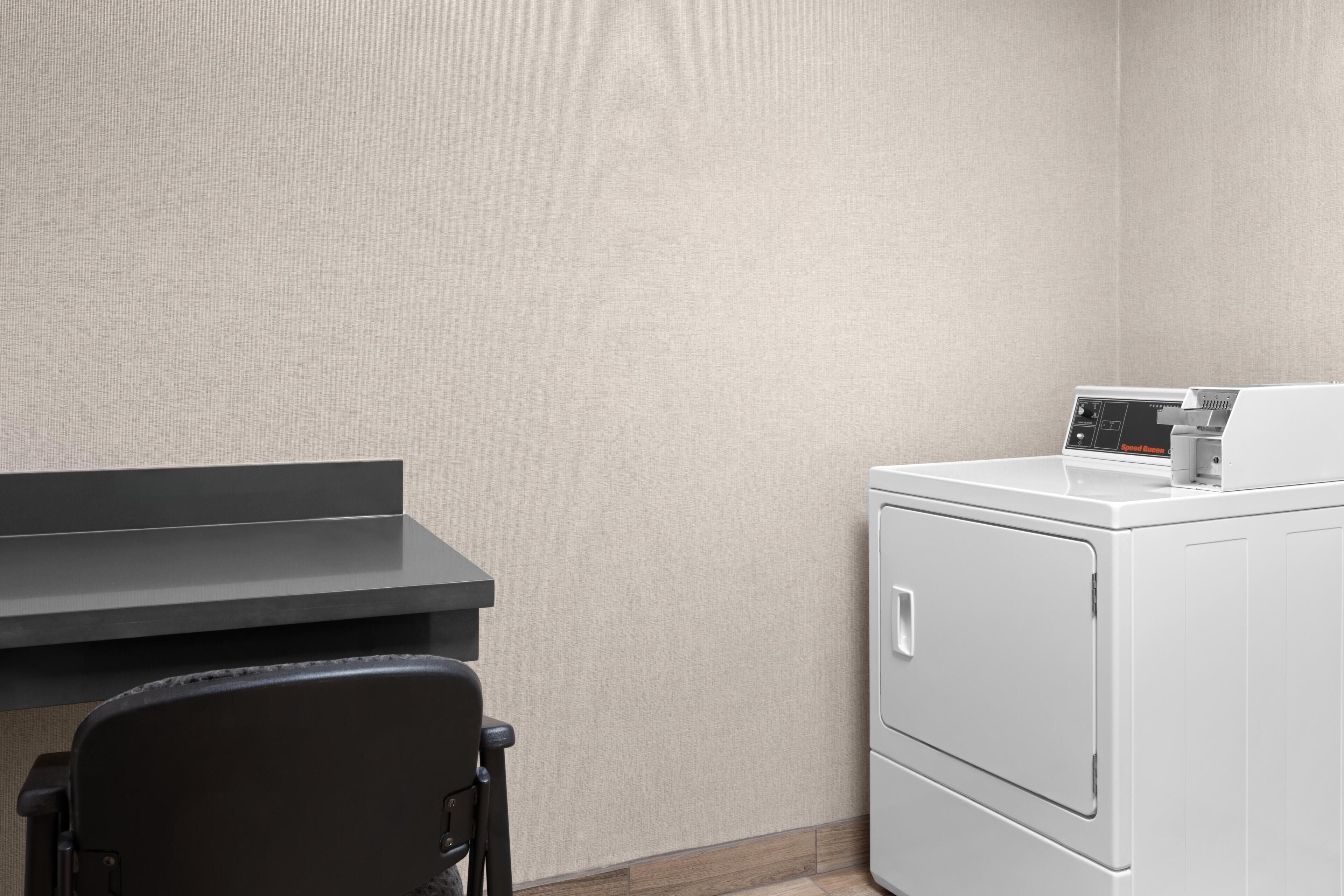 A laundry area with a washing machine, a dryer, and a chair.