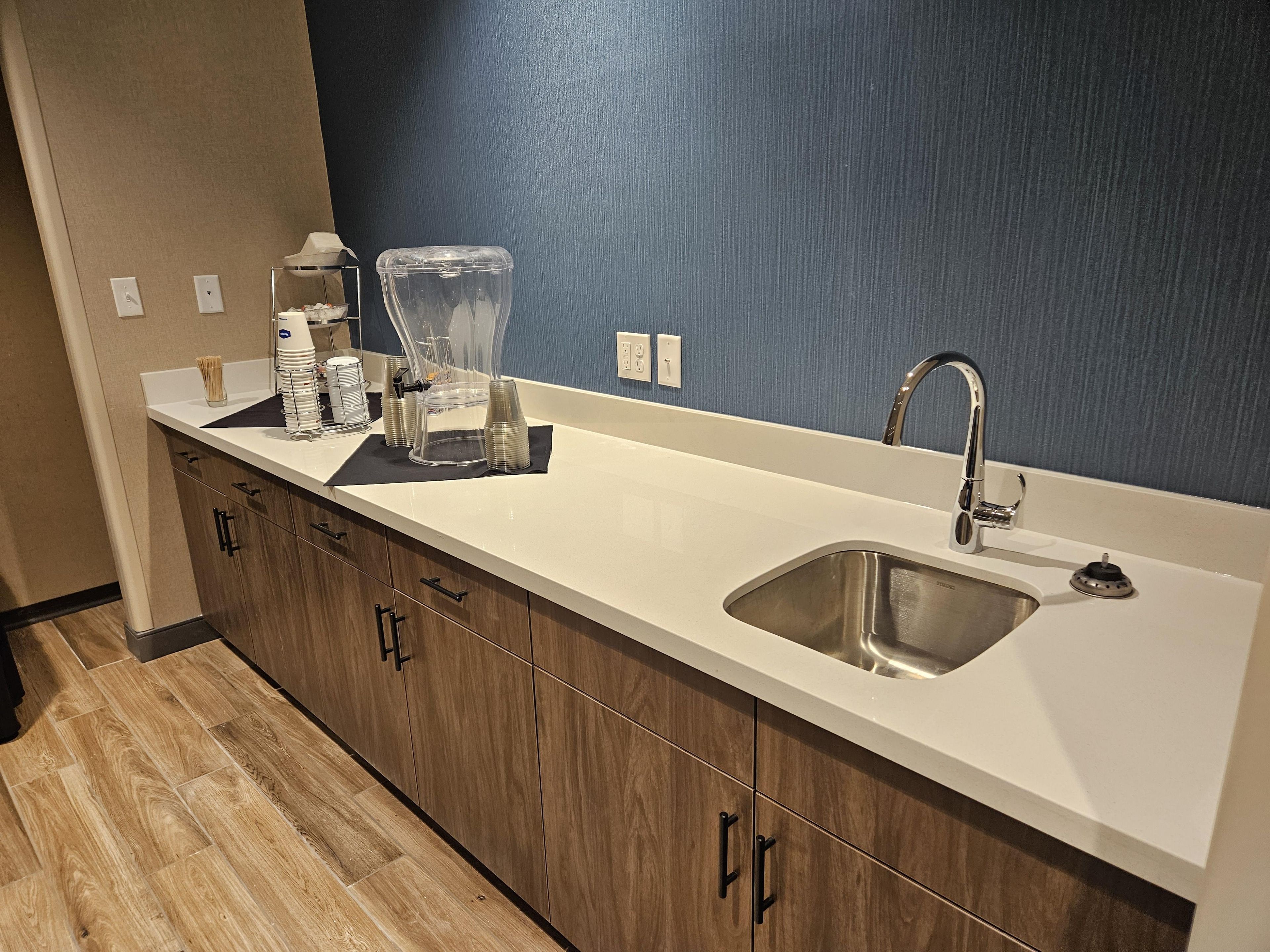 A modern kitchen with a stainless steel sink, wooden cabinets, and a blue accent wall.