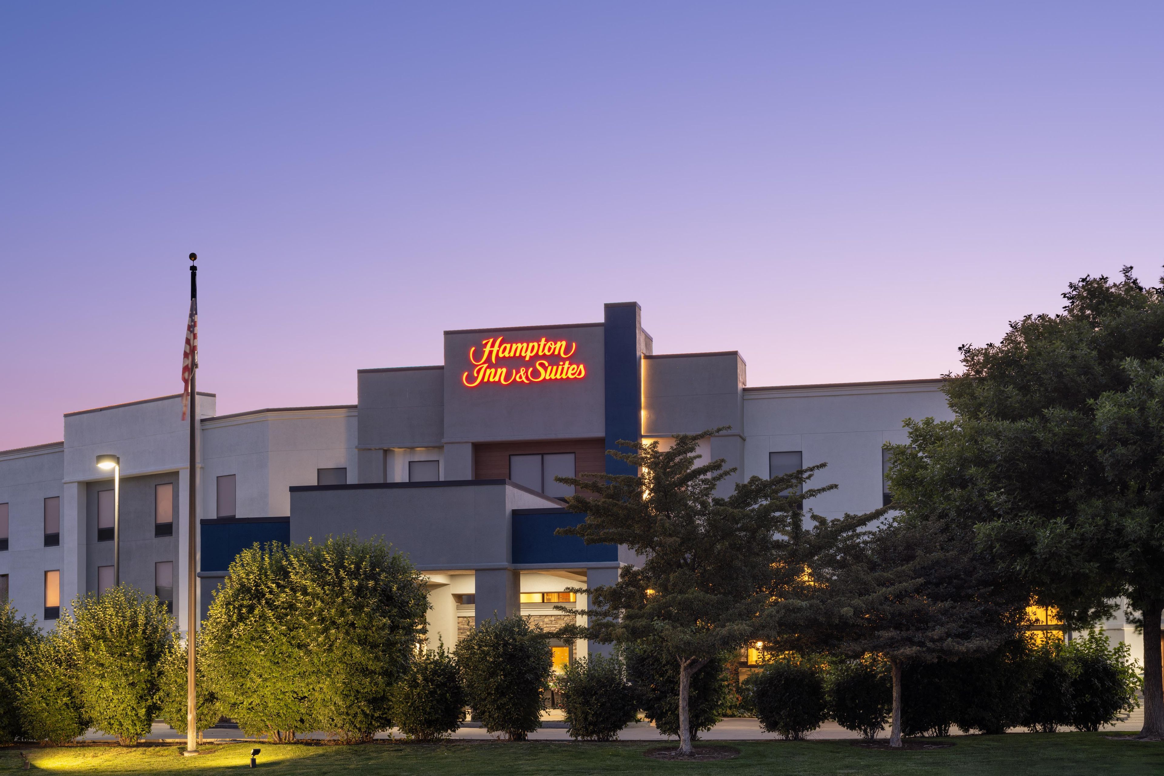 Un edificio moderno con un letrero llamativo de Hampton Inn & Suites.