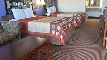 Habitación de hotel con una cama grande, un escritorio, una silla y un baño visible a través de un arco.