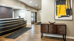 A hotel reception area with a curved reception desk, a refrigerator stocked with snacks, a vending machine, and a large abstract painting on the wall. - Residence Inn by Marriott Rochester Mayo Clinic Area (Rochester)