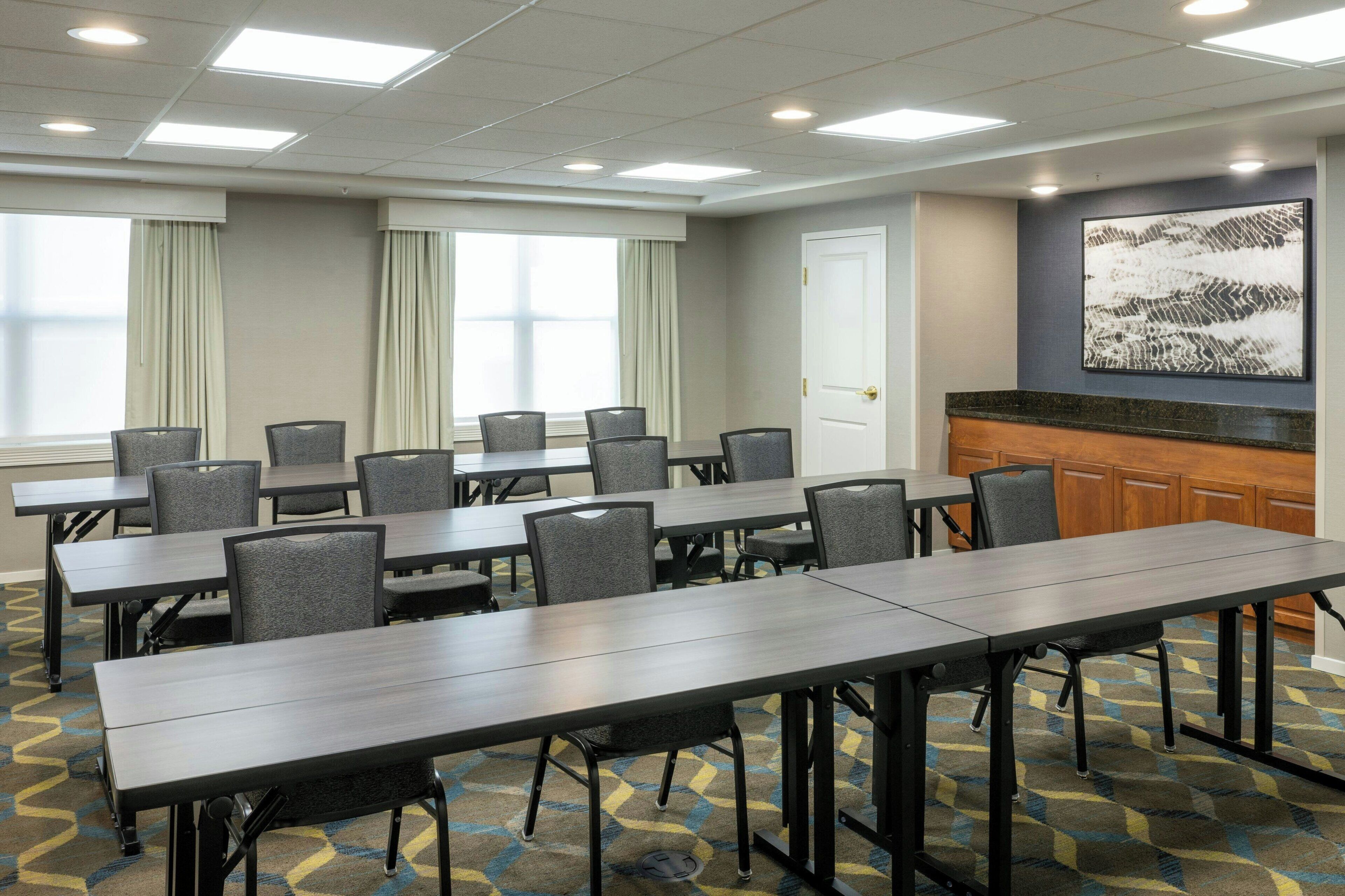 A conference room with a long table and multiple chairs, a reception desk, and a large abstract painting on the wall.