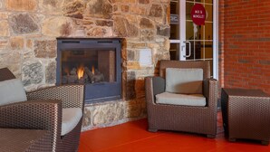 Una chimenea de piedra con fuego, muebles de mimbre y un letrero que dice "MIX & MINGLE!"