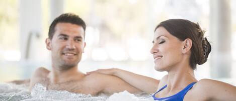 A couple in a hot tub with visible bubbles, suggesting a spa setting.