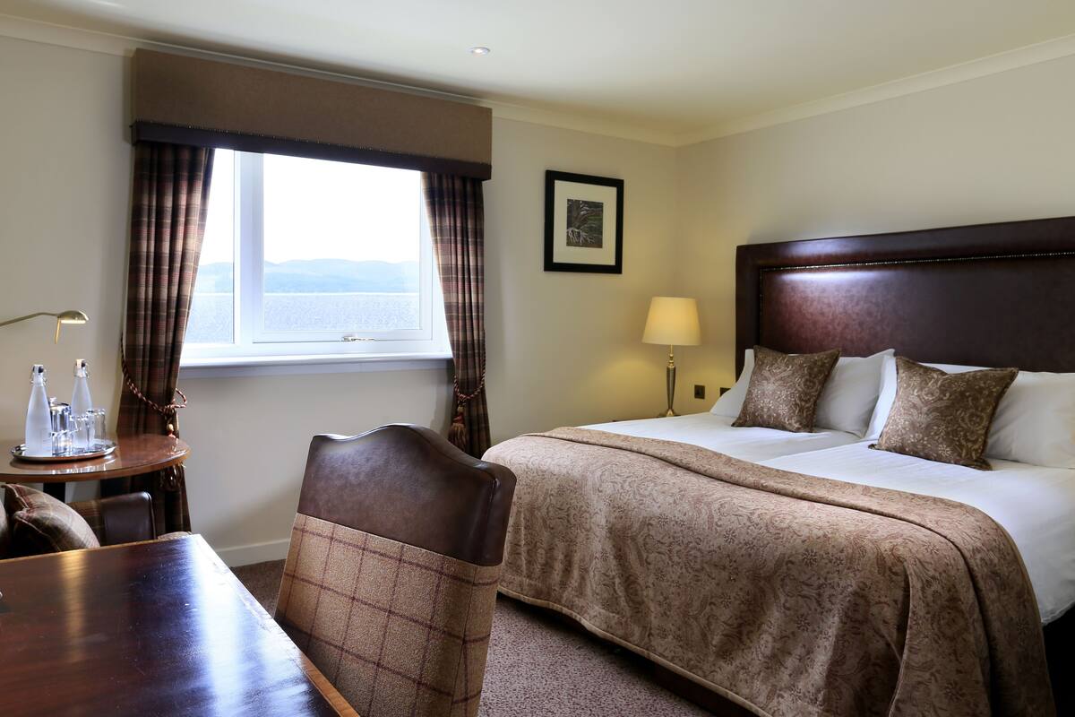 A hotel room with a large bed, a dining table, and a view of the sea.