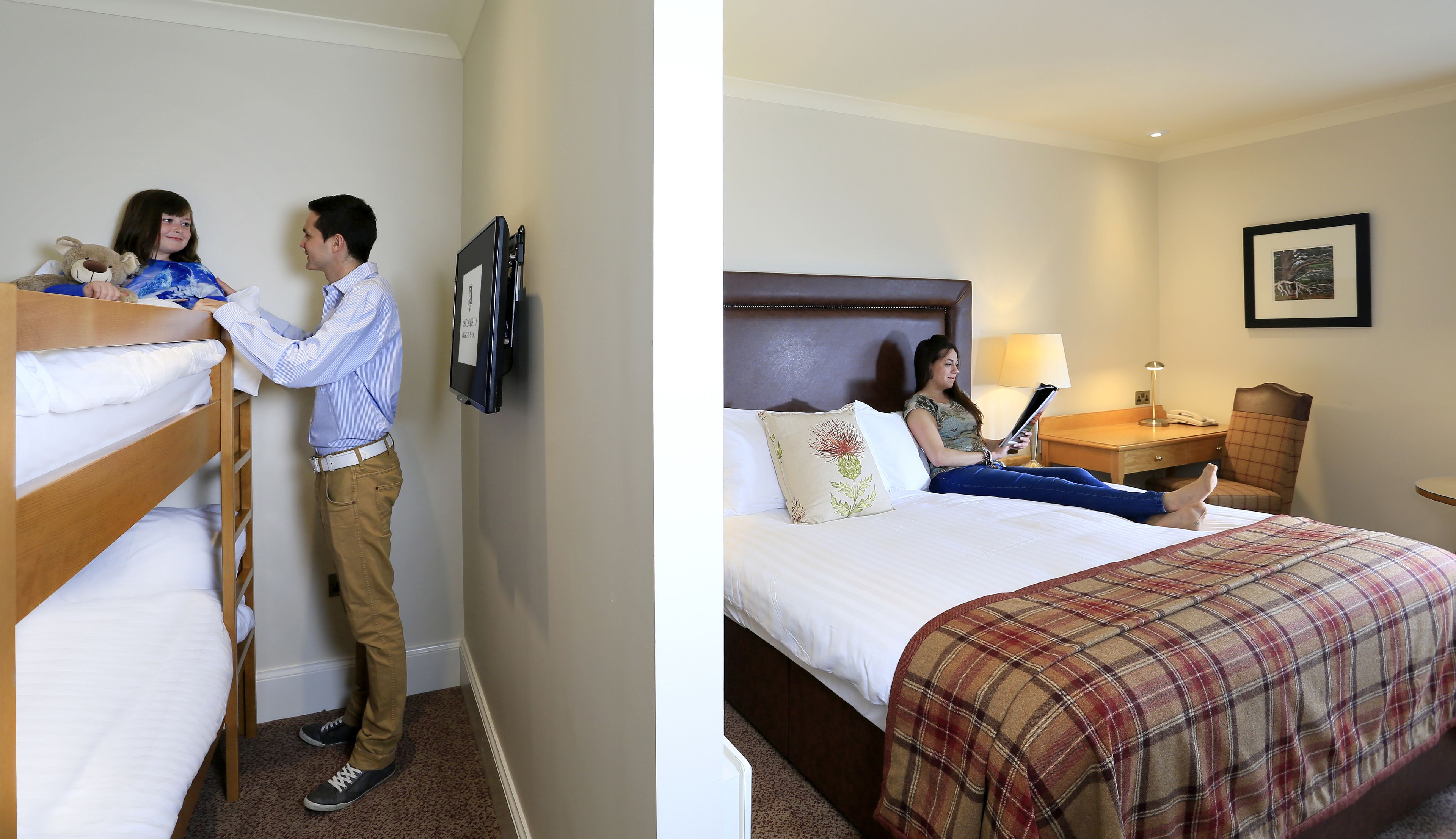 A hotel room with a bunk bed, a single bed, a nightstand, a lamp, and a framed picture on the wall.