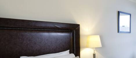 A neatly made bed with a plaid bedspread, a wooden headboard, and a bedside lamp.