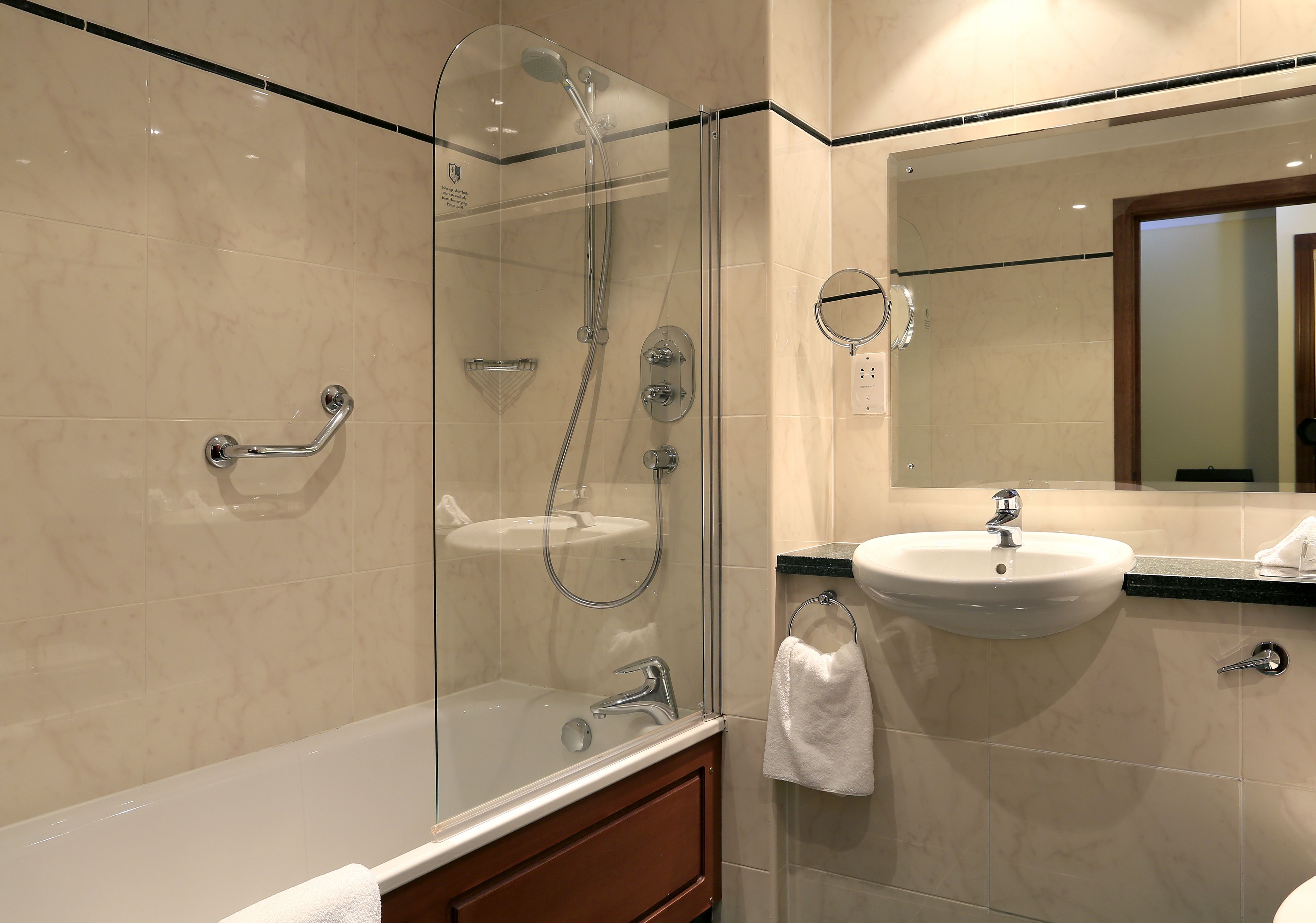 A modern bathroom with a glass-enclosed shower, a sink, and a vanity with a mirror.