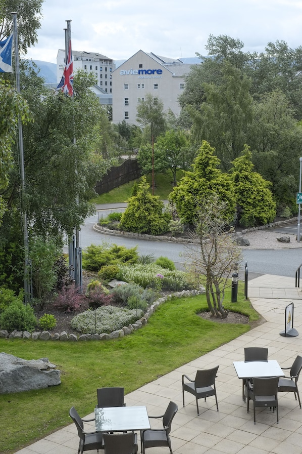 A hotel courtyard with outdoor seating, a flagpole, and a building with 'avie more' signage.
