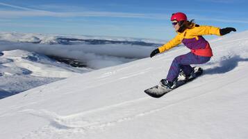 Un snowboardeur sur une pente enneigée, avec un ciel dégagé et des nuages en arrière-plan.