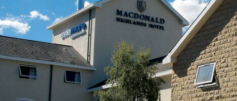 The Macdonald Highlands Hotel with a sign indicating it is part of the Avie More Highland Resort.