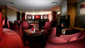 Cómoda sala de estar con asientos tapizados en rojo, chimenea y televisor.