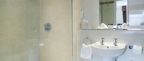 Une salle de bain moderne avec une douche en verre, un lavabo blanc et un miroir au-dessus du lavabo.