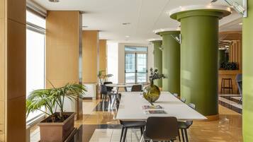 A modern conference room with a white table, black chairs, and green columns.