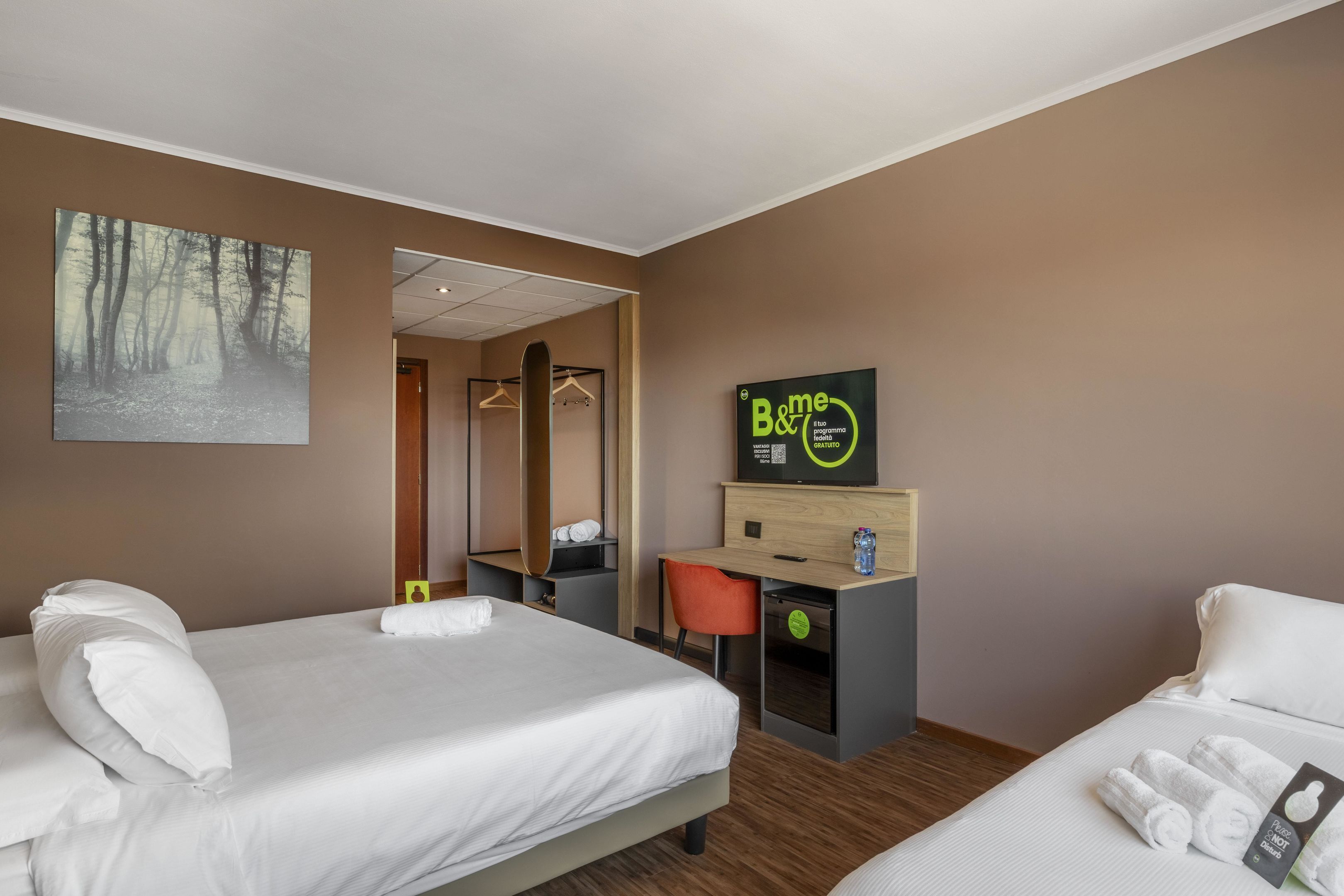 Una habitación de hotel con dos camas, un escritorio y un espejo.
